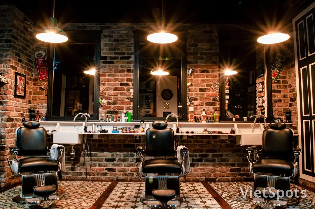 Barbershop interior — 3 ghế barber cổ điển, tường brick đỏ, đèn treo vàng