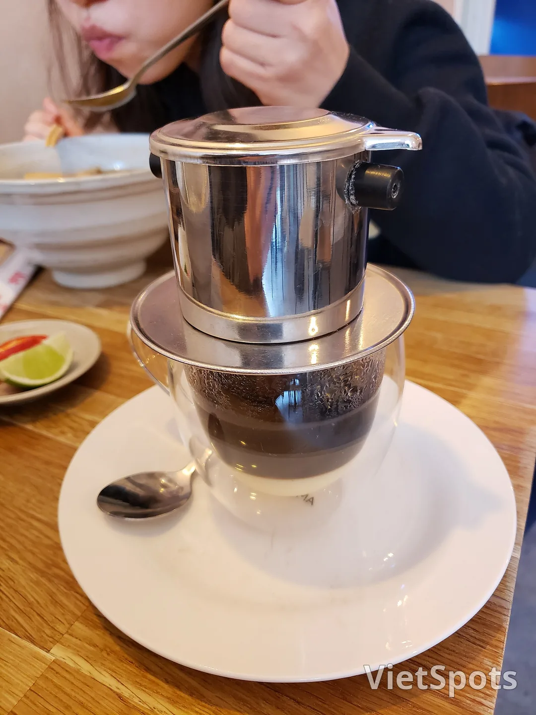 Phin cà phê nhỏ giọt xuống ly có lớp sữa đặc dưới đáy