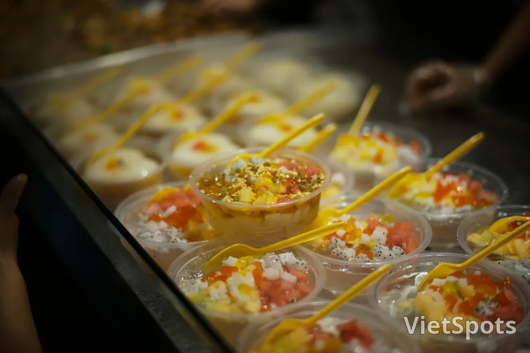 Nhiều ly chè trong suốt với topping đủ màu — thanh long, xoài, thạch, hạt lạc, rau câu