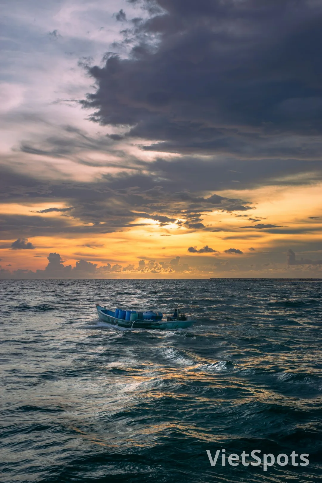 Thuyền cá Việt Nam nhỏ dưới bầu trời hoàng hôn cam tím trên biển — cảnh coastal islet