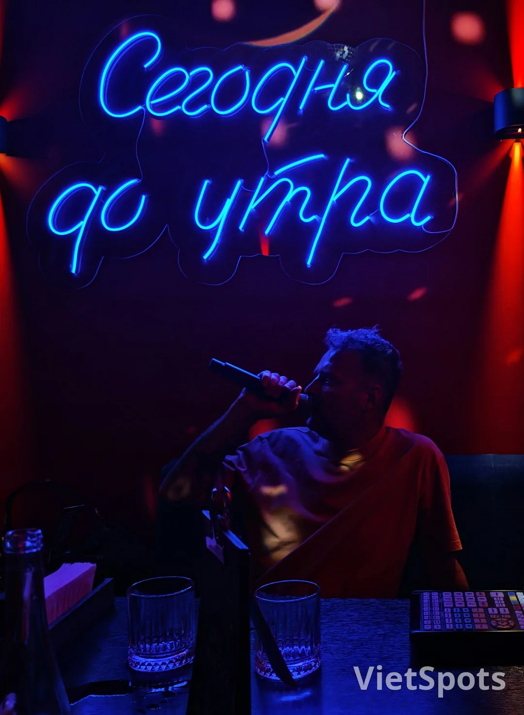 Phòng karaoke với đèn neon xanh + microphone + không gian tối vibe party