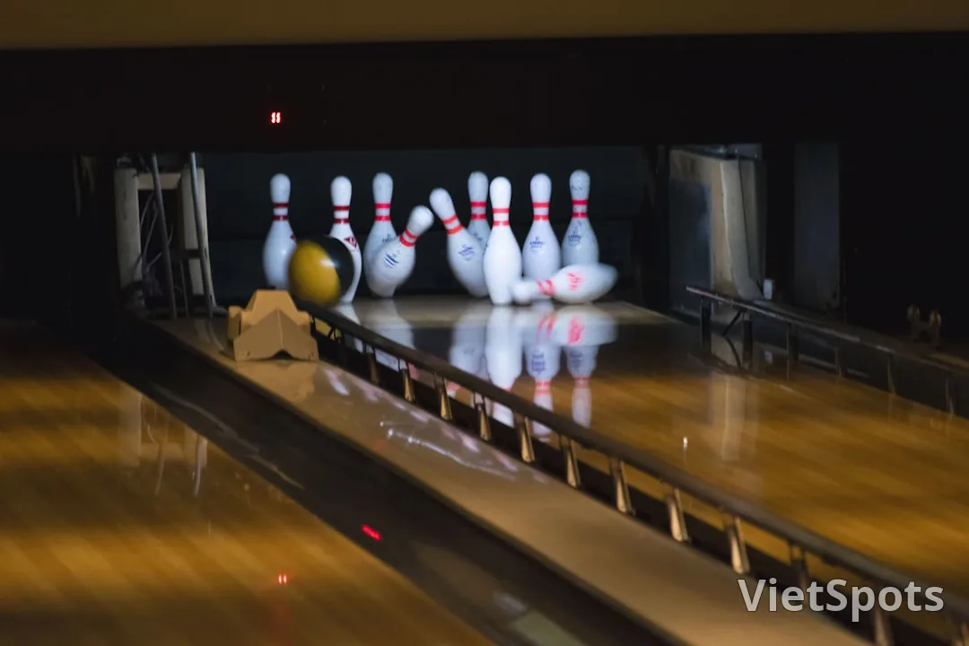 Bowling alley với bóng vàng vừa đánh trúng pin trắng đỏ, motion blur