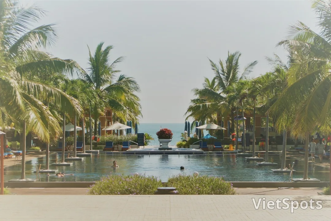 Resort ven biển với hồ bơi vô cực + palm trees hai bên + view đại dương xa xa