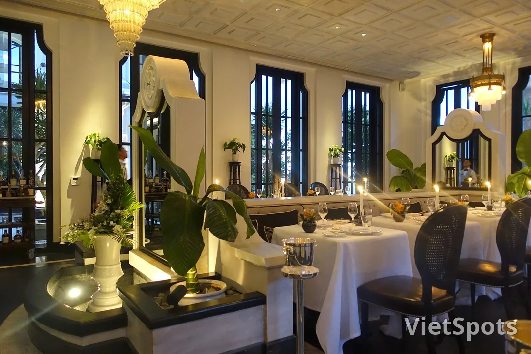 Nội thất nhà hàng tông trắng đen, đèn chùm pha lê, bàn trải khăn trắng và nến