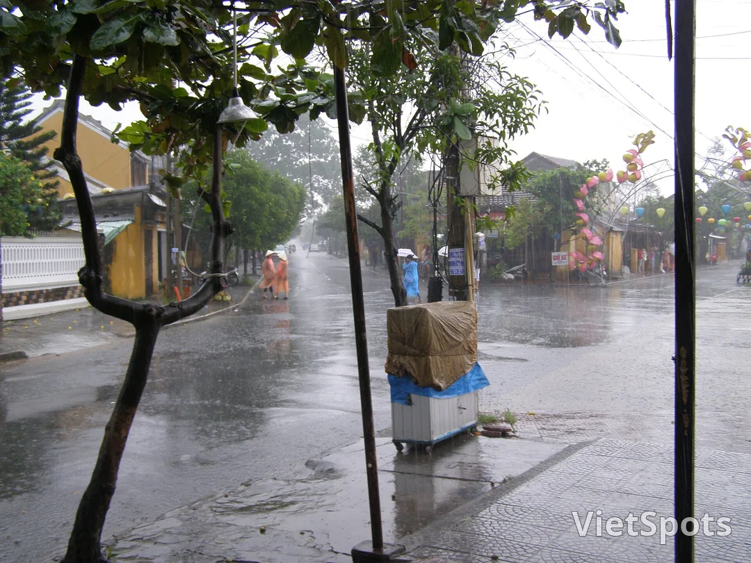 Ngã tư phố cổ Hội An giữa cơn mưa lớn, mặt đường loang nước, đèn lồng ướt rũ hai bên