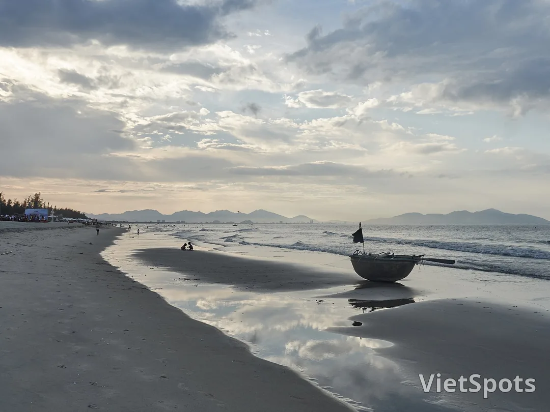 Bãi biển An Bàng lúc chiều muộn, một chiếc thuyền thúng nằm trên mặt cát ướt phản chiếu mây trời
