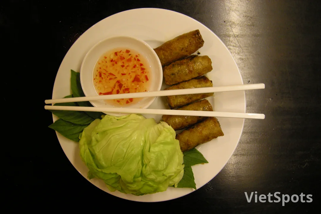 Đĩa ram cuốn chả giò giòn rụm ăn kèm cải xanh và nước mắm chấm
