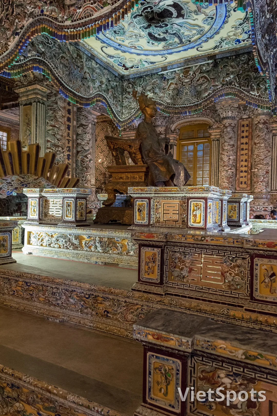 Nội thất cung Thiên Định trong lăng Khải Định, tường và trần khảm kín mảnh sành sứ thuỷ tinh nhiều màu, tượng vua ngồi trên ngai dưới bửu tán