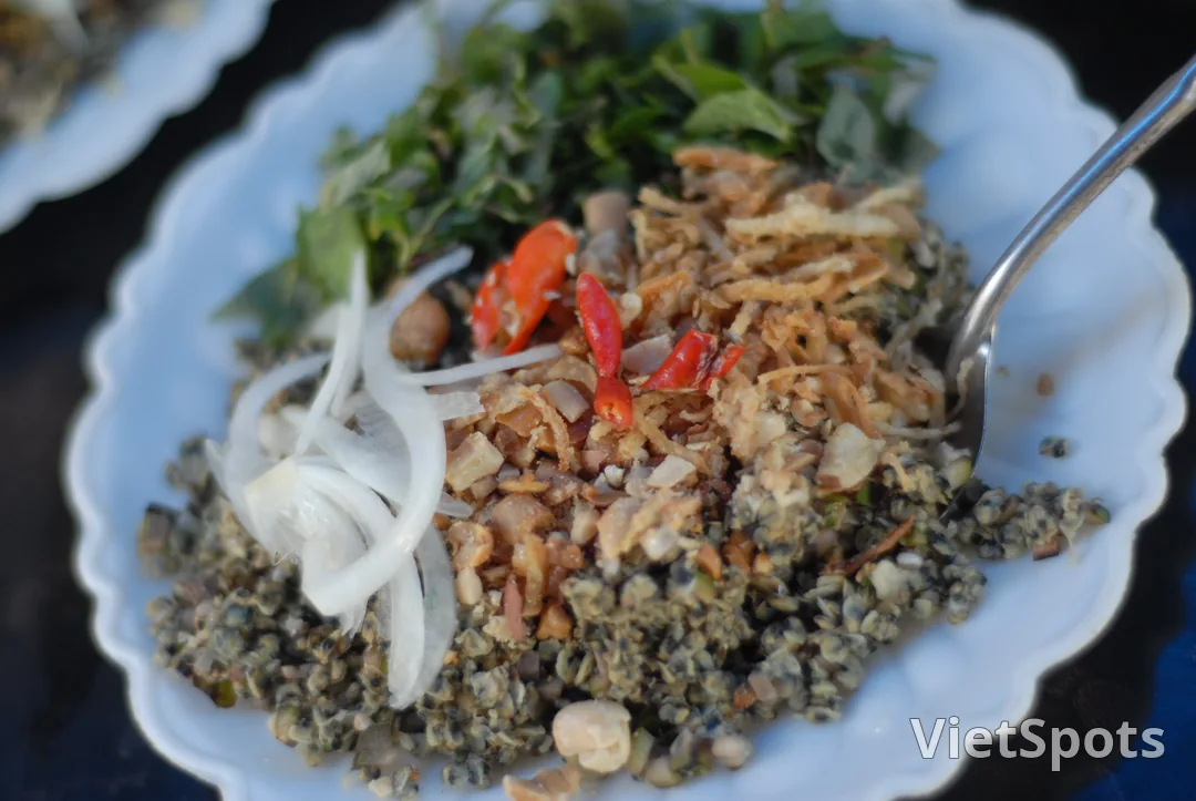 Đĩa hến trộn với rau thơm, hành tây thái mỏng, tóp mỡ, đậu phộng và mấy trái ớt đỏ để nguyên