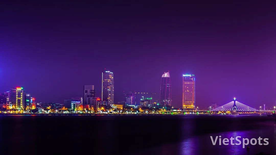 Toàn cảnh Đà Nẵng về đêm dưới nền trời tím, dãy cao ốc ven sông Hàn và cầu Sông Hàn thắp đèn trắng bên phải