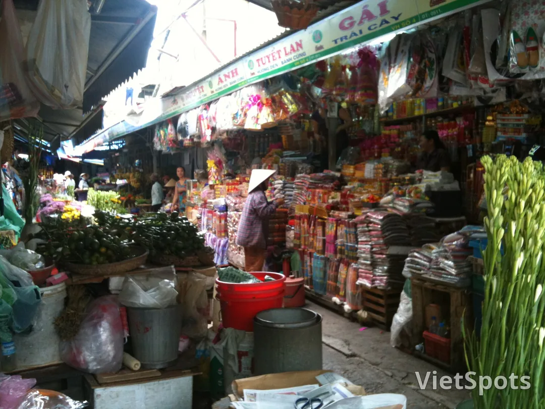 Lối đi trong chợ Đà Nẵng, hai bên là sạp hoa tươi, hương, bánh kẹo và đồ khô chất cao
