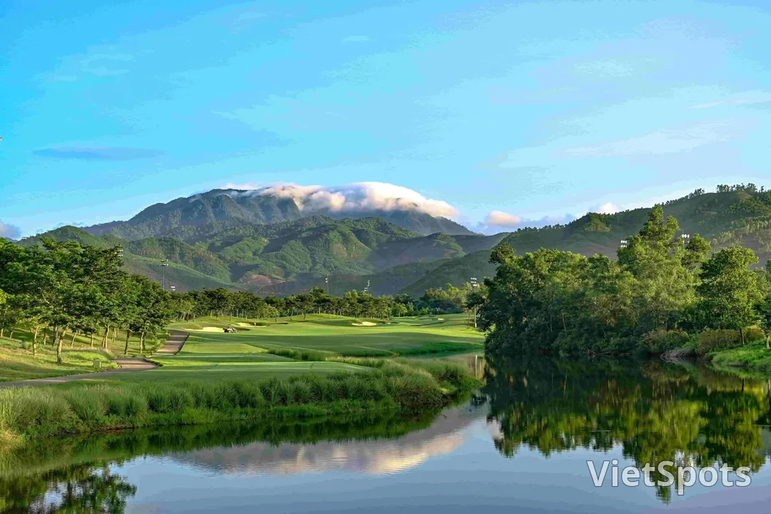 Một hố golf ở Bà Nà Hills nằm bên hồ nước, phía sau là dãy núi có mây phủ