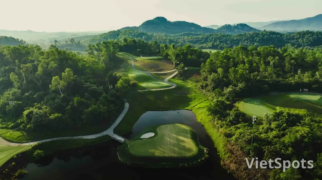 Green đảo của sân Bà Nà Hills nằm giữa hồ nước, bao quanh là rừng cây và các cột đèn chiếu sáng ban đêm