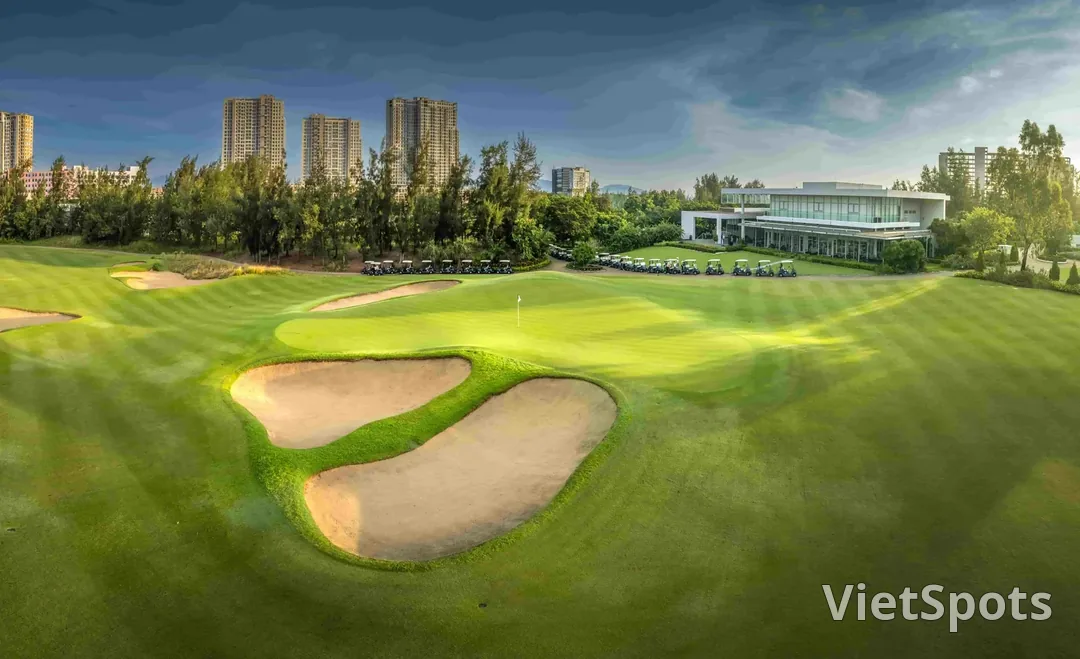 Green và clubhouse của Montgomerie Links nhìn từ fairway, hai bunker lớn chắn trước green