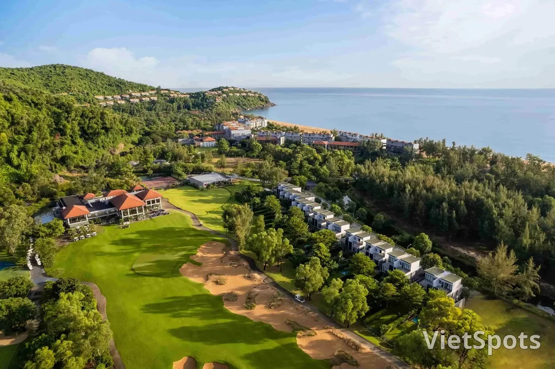 Sân Laguna Lăng Cô nhìn từ trên cao, fairway nằm giữa sườn núi phủ rừng và bãi biển cong hình vòng cung