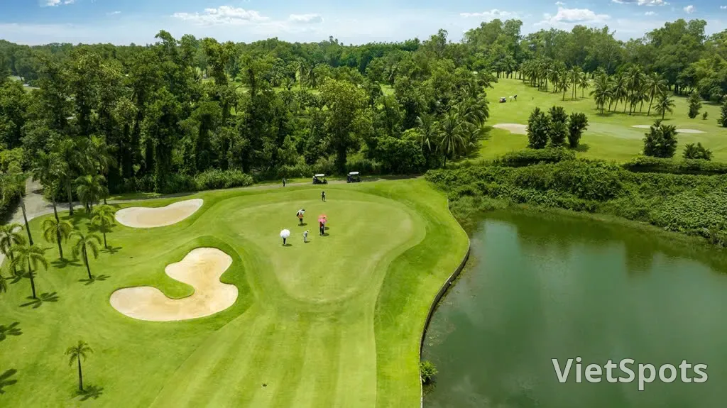 Nhóm golfer đang chơi trên green ở sân Sông Bé, bên phải là hồ nước, xung quanh là rừng cây và hàng cau