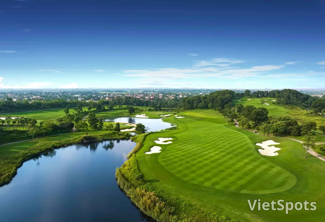 Một fairway rộng ở Sky Lake uốn quanh hồ nước lớn, phía xa là làng mạc vùng đồng bằng Bắc Bộ