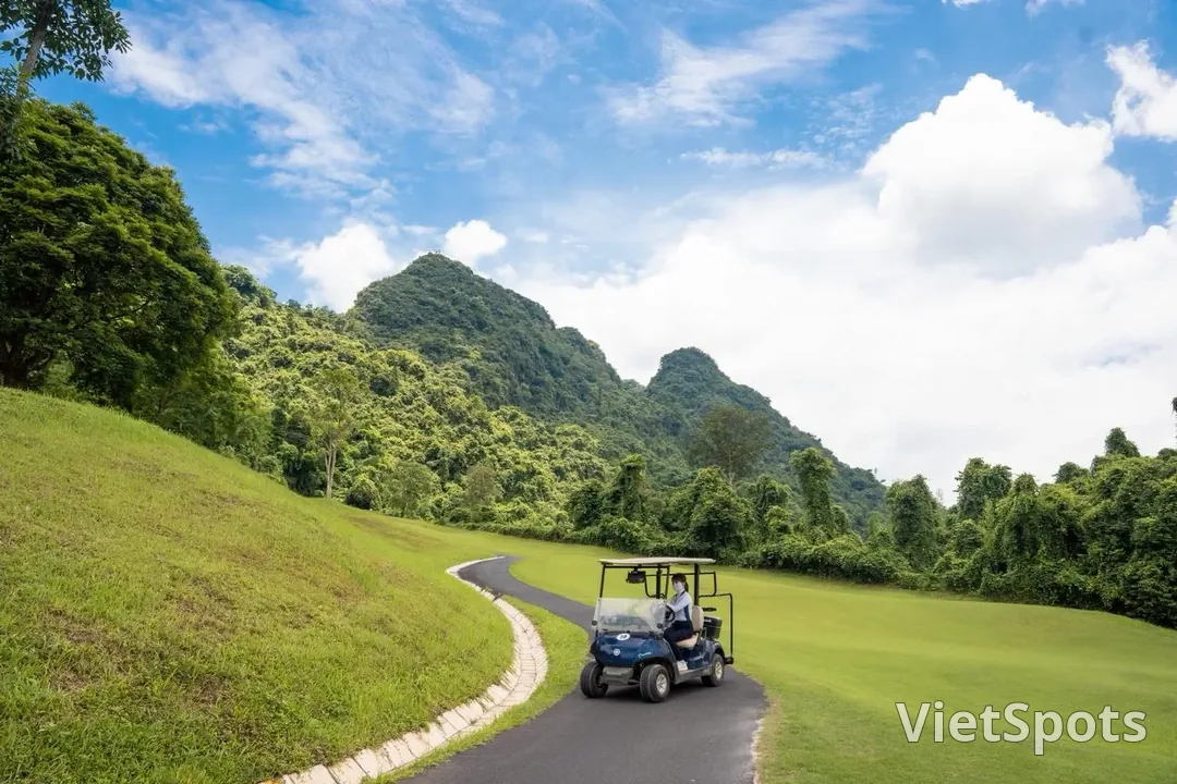 Một chiếc xe điện chạy trên đường nhỏ ven fairway ở Phoenix, phía sau là núi đá vôi và trời nhiều mây trắng