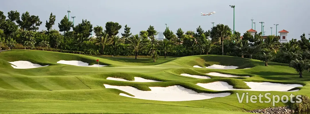 Một máy bay vừa cất cánh bay ngang phía trên green sân golf Tân Sơn Nhất, phía dưới là cụm bẫy cát trắng uốn lượn
