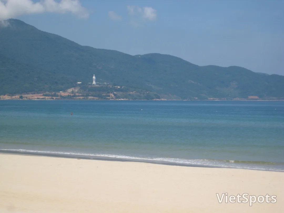 Bãi biển Mỹ Khê nhìn về phía bán đảo Sơn Trà, tượng Phật Bà trắng nhỏ xíu đứng trên mỏm núi xanh bên kia vịnh