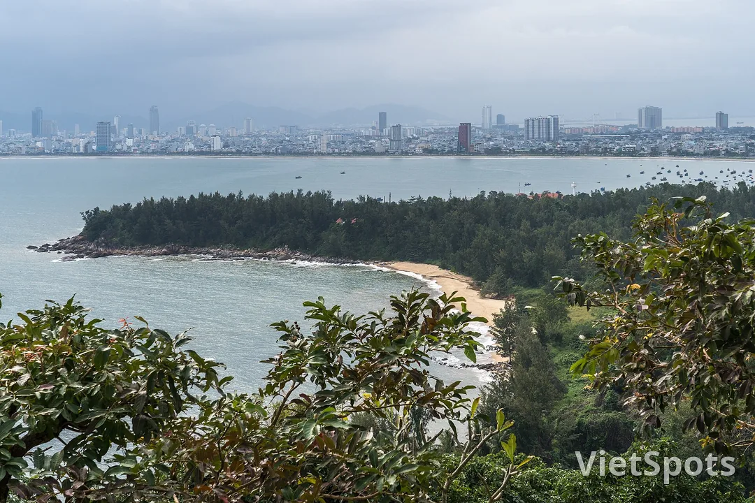 Nhìn từ Sơn Trà xuống: một doi đất phủ rừng, vịnh nước lặng và dãy nhà cao tầng Đà Nẵng trải dài phía xa