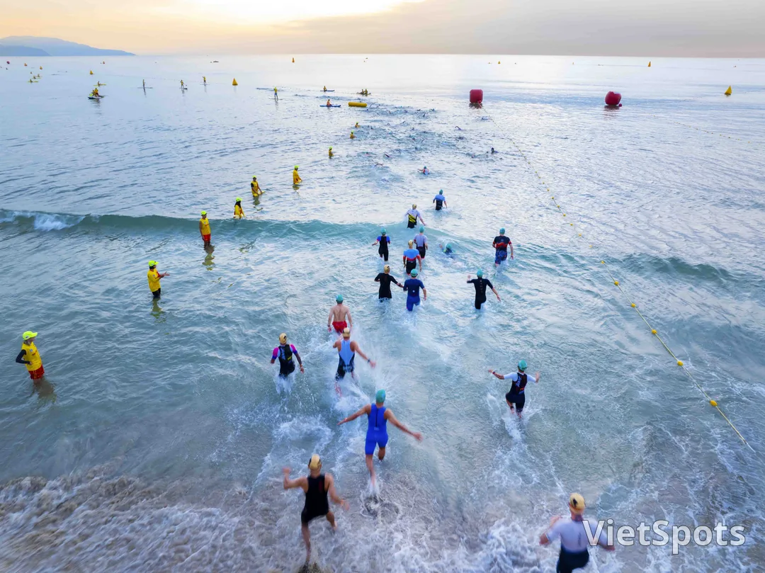 Vận động viên IRONMAN lội ra biển Đà Nẵng ở phần thi bơi, nhìn từ trên cao, phao đỏ và vàng đánh dấu đường bơi