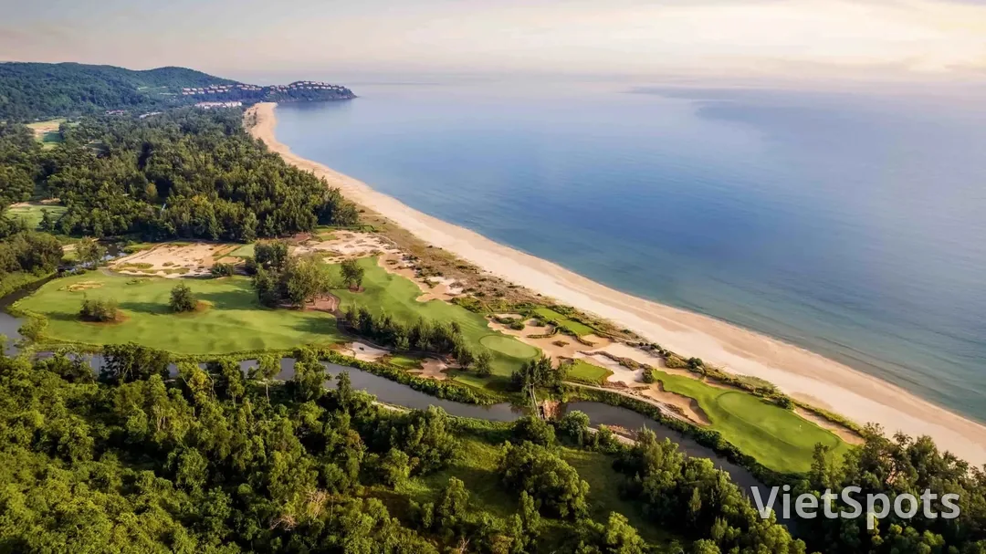 Sân golf Laguna Lăng Cô nhìn từ trên cao: các hố golf chạy dọc bãi cát dài ven biển, một con suối uốn quanh rìa rừng, xa xa là các biệt thự trên sườn núi