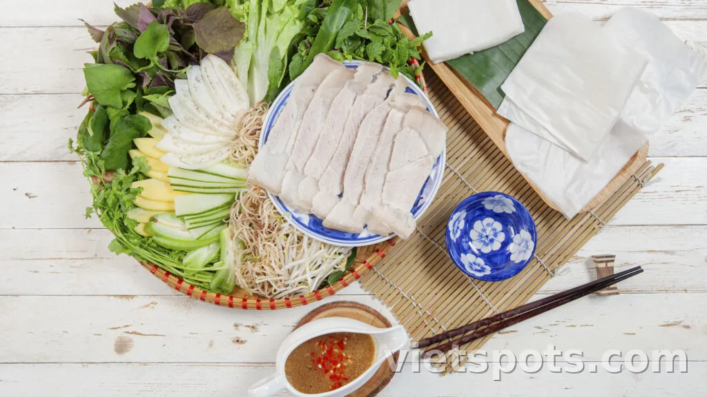 Rổ bánh tráng cuốn thịt heo — thịt luộc, giá đỗ, xoài xanh sợi, rau sống, bánh tráng mỏng và chén mắm nêm ớt