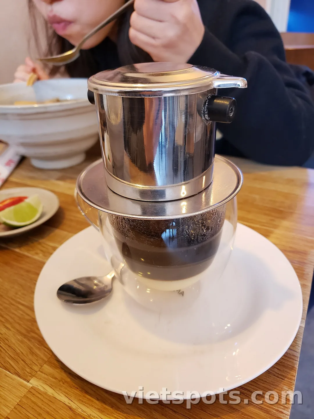 Phin cà phê nhỏ giọt xuống ly có lớp sữa đặc dưới đáy