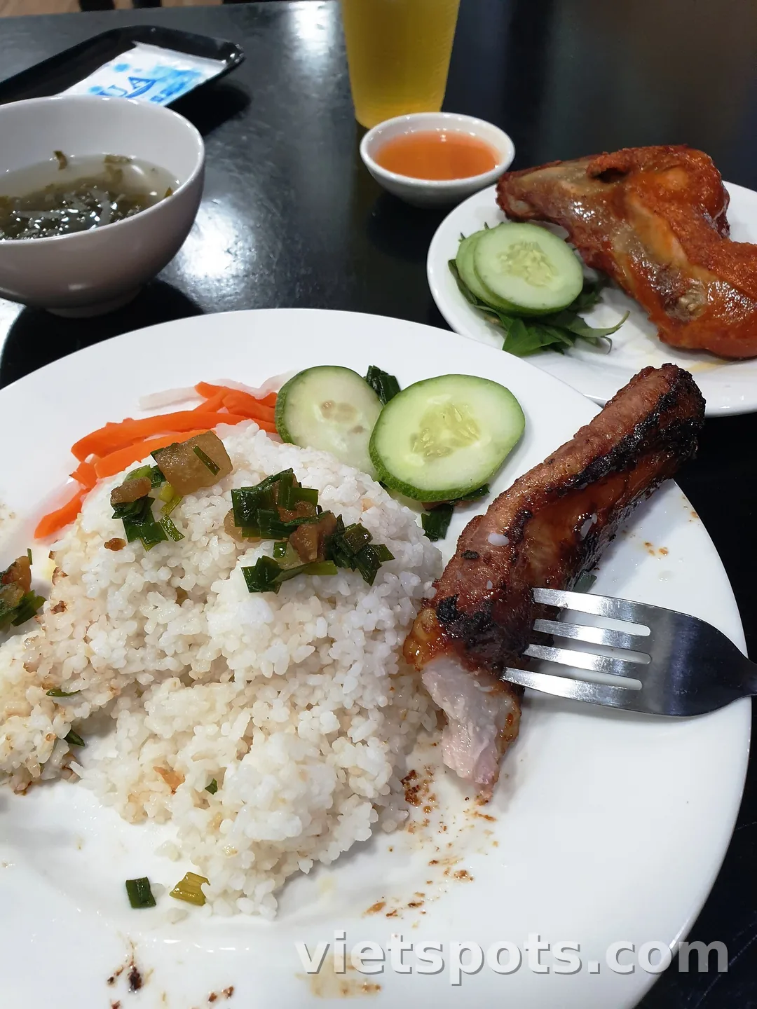 Đĩa cơm tấm sườn nướng với đồ chua, dưa leo và chén canh