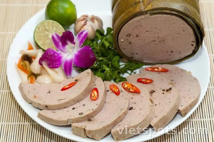 Chả bò Đà Nẵng gói lá chuối + lát tròn xám hồng có tiêu + ớt đỏ + chanh + tỏi + ngò + dưa hành