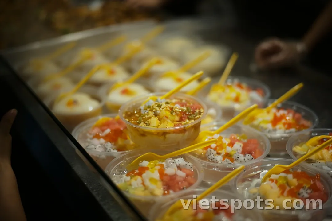 Nhiều ly chè trong suốt với topping đủ màu — thanh long, xoài, thạch, hạt lạc, rau câu