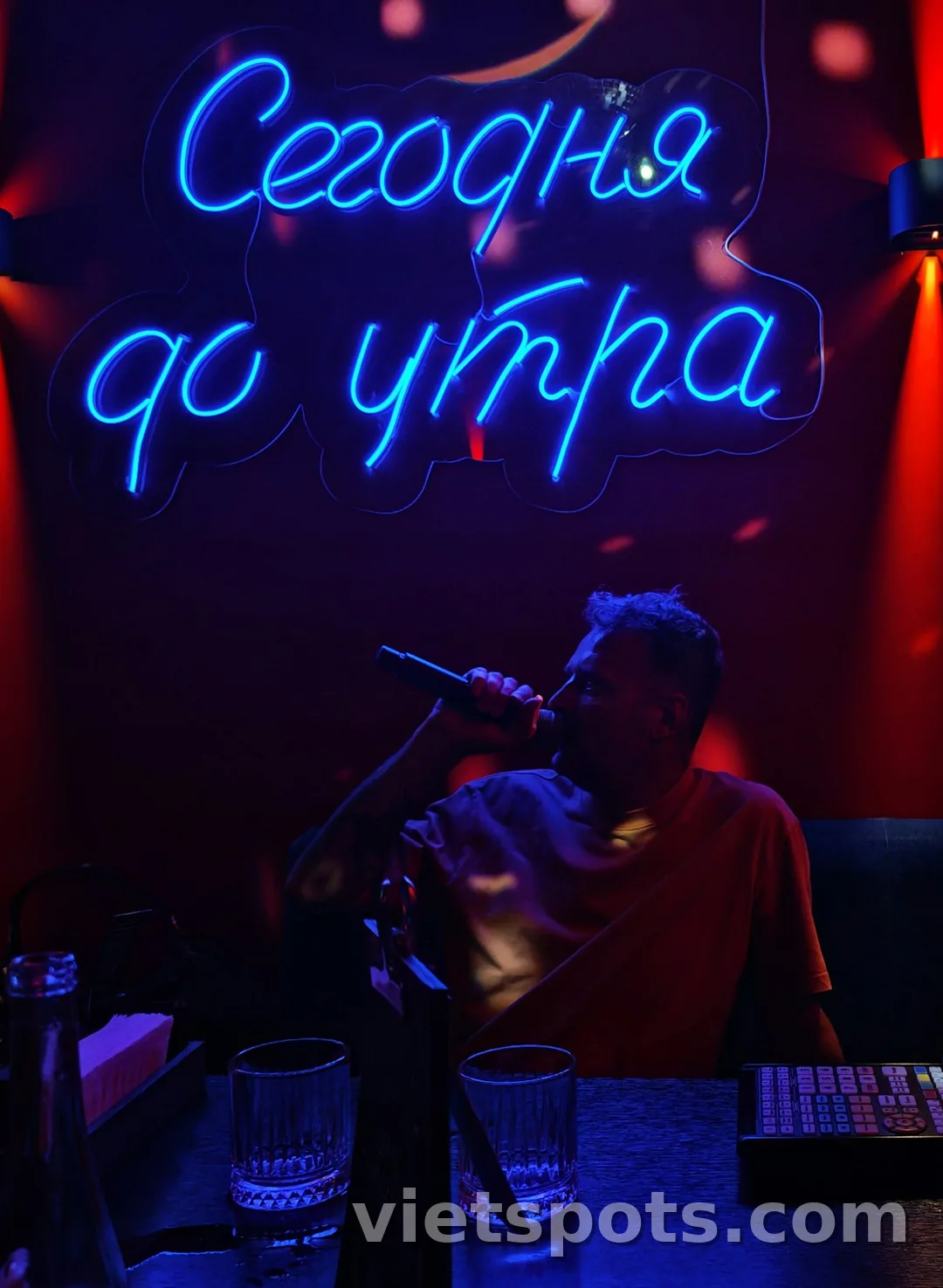 Phòng karaoke với đèn neon xanh + microphone + không gian tối vibe party
