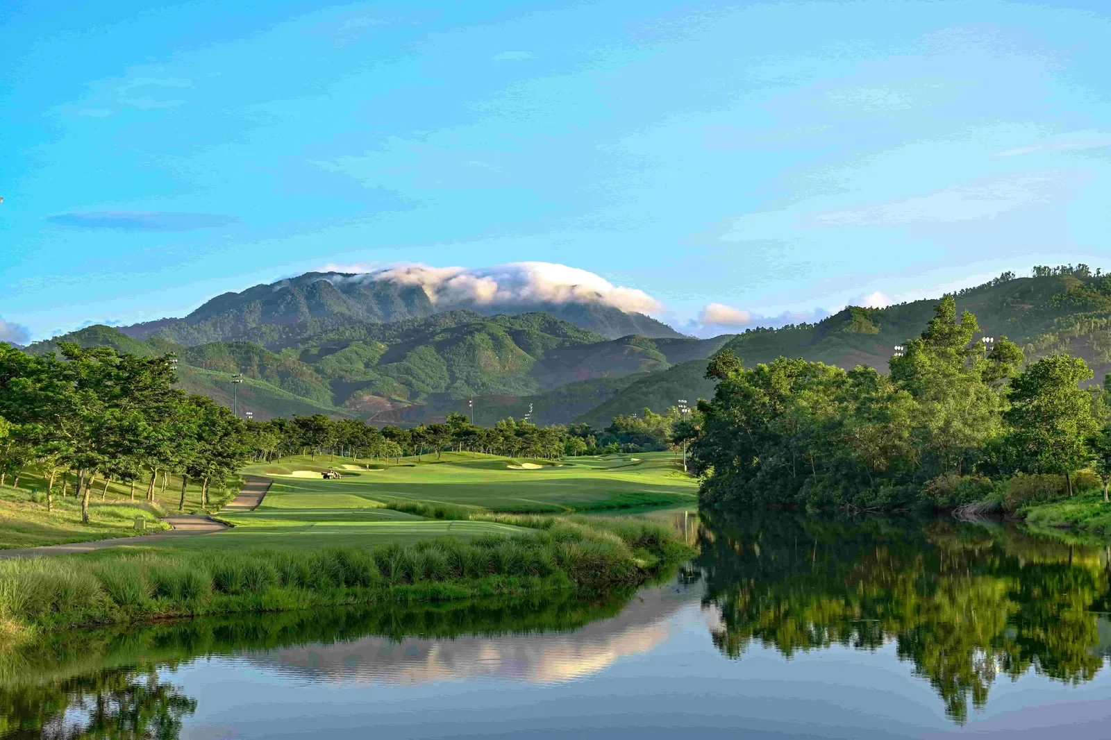 Một hố golf ở Bà Nà Hills nằm bên hồ nước, phía sau là dãy núi có mây phủ