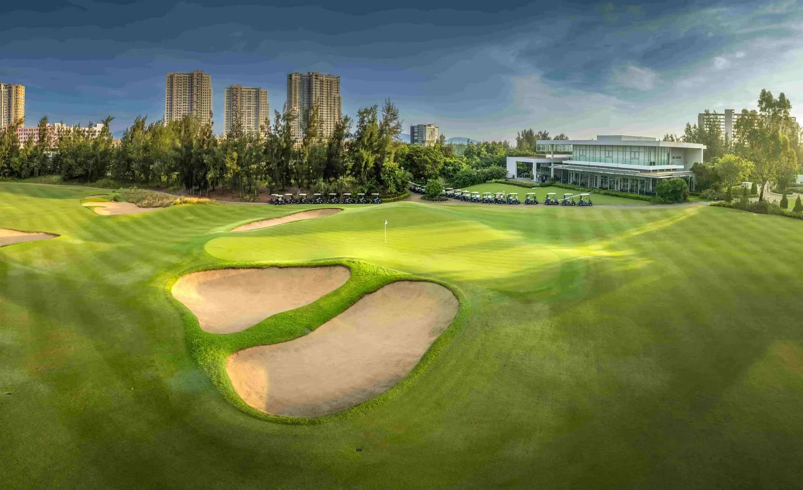 Green và clubhouse của Montgomerie Links nhìn từ fairway, hai bunker lớn chắn trước green